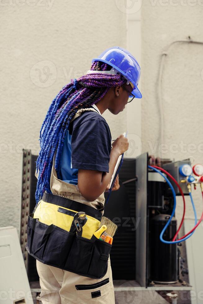 Proficient worker commissioned for leaks checking, making sure all air conditioner vents are clear of dust. Qualified electrician doing external hvac system probe, finishing paperwork photo