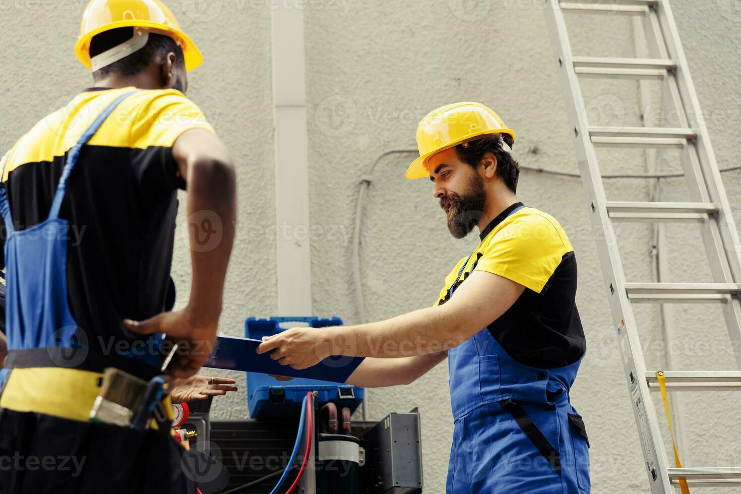 Precise servicemen repairing and maintaining heating, ventilation, and air conditioning systems. Experienced professionals commissioned for condenser annual checkup, writing report on clipboard photo