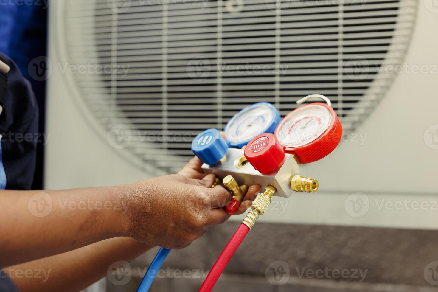 Close up of trained engineer holding manifold gauges used for checking air conditioner refrigerant. Certified technician using benchmarking barometer for high or low freon levels of hvac system photo