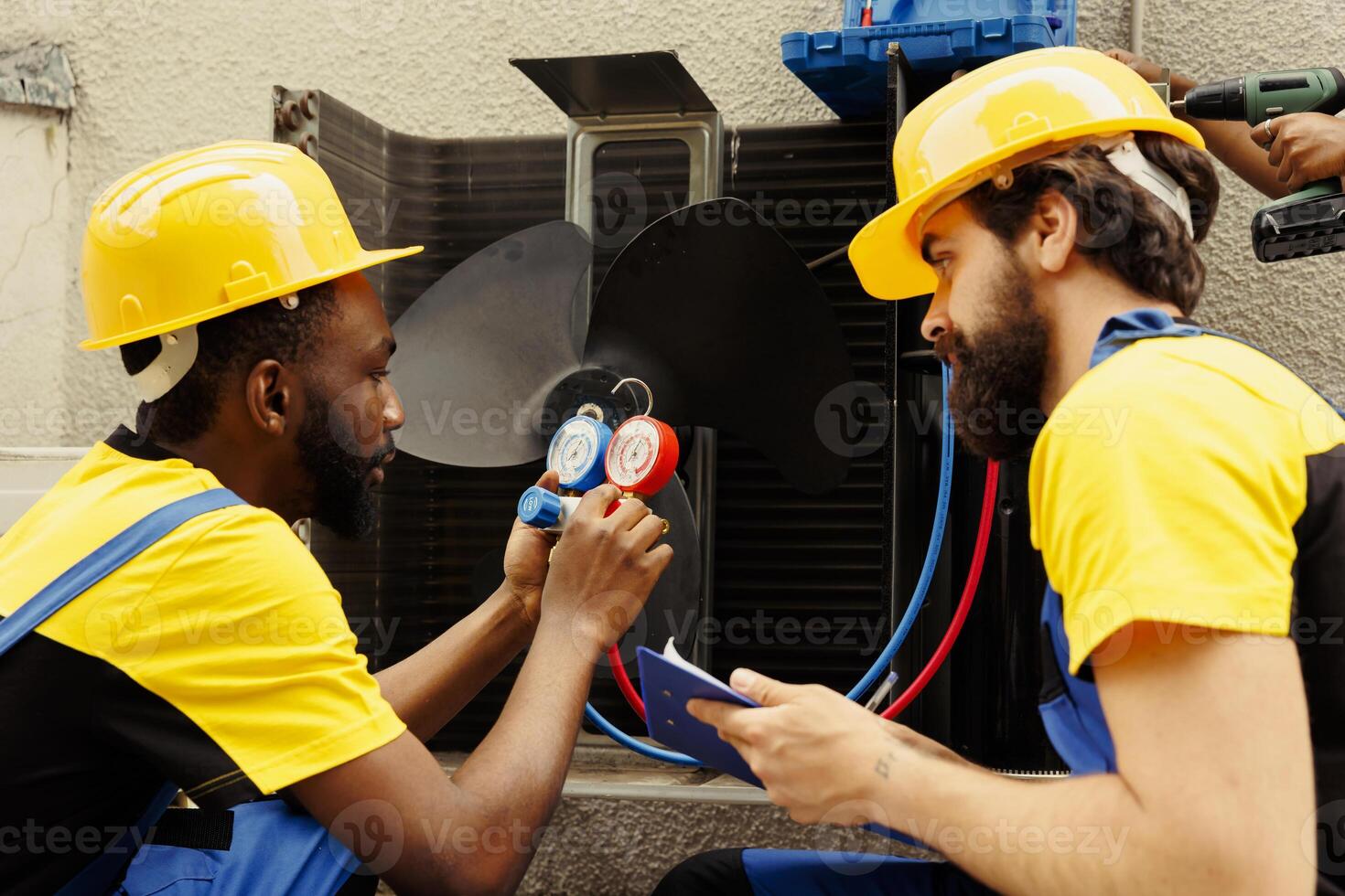 Meticulous wiremen expertly refilling freon in external air conditioner while using manifold measurement device to closely measure the pressure in HVAC system, ensuring perfect cooling performance photo