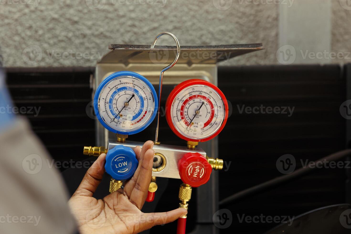 Close up of manifold gauges able to find out of order expansion valve, moisture intrusion and other hvac system internal problems. Licensed serviceman using professional gadget to read pressure levels photo