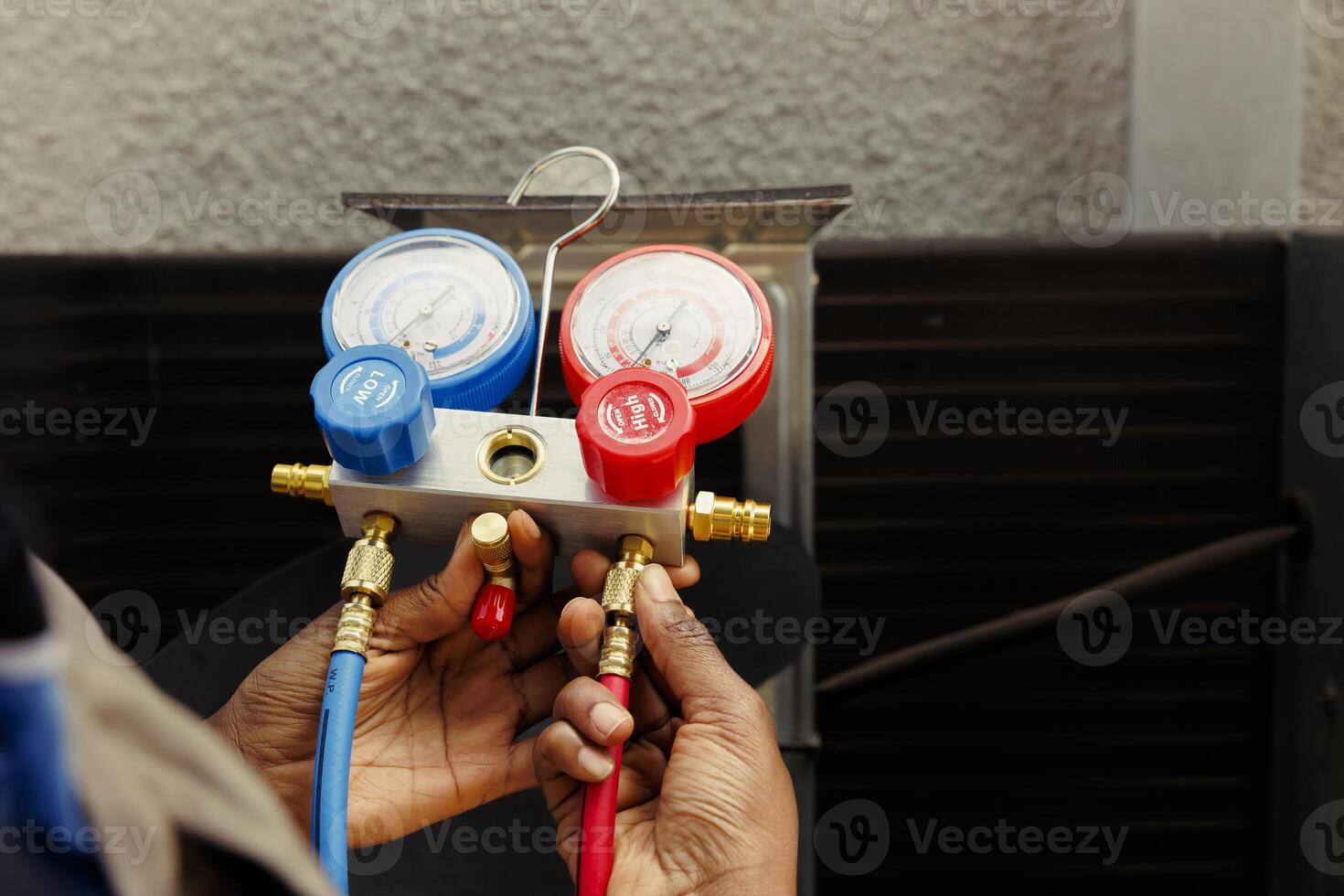 Manifold gauges able to detect excessive refrigerant in hvac system and moisture intrusion. Precise serviceman using ac gauges vacuum pump to read pressure levels, comissioned by client, close up photo