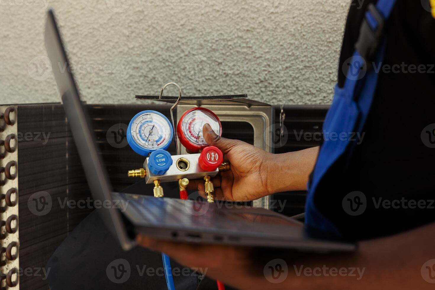 Seasoned mechanic restoring cooling capacity of air conditioning system by removing existing refrigerant, inspecting system for leaks and recharging with new freon to prevent damage to compressor photo