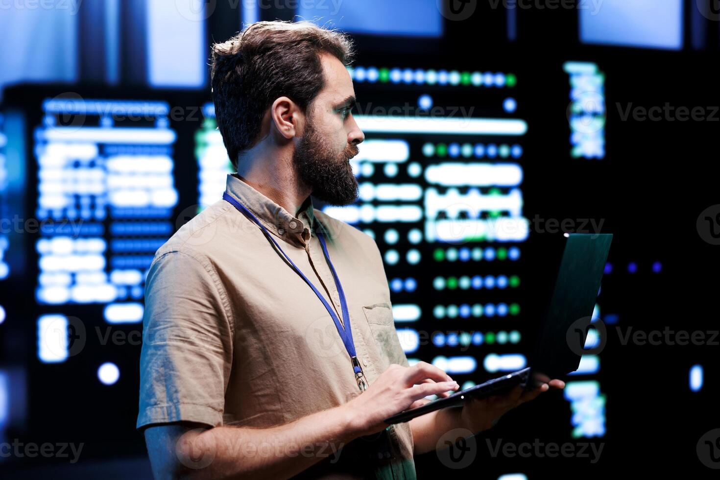 Proficient technician using laptop to check server hub devices. High tech rigs in data storage and cloud computing business service providing processing for several workloads photo