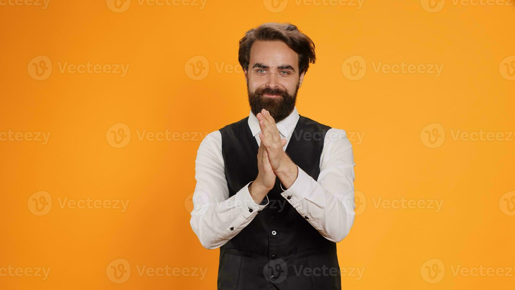 Passionate waiter applauds with both hands in studio to congratulate someone on recent performance. Young man cheering while he serves as butler in food establishment, confidence boost. photo