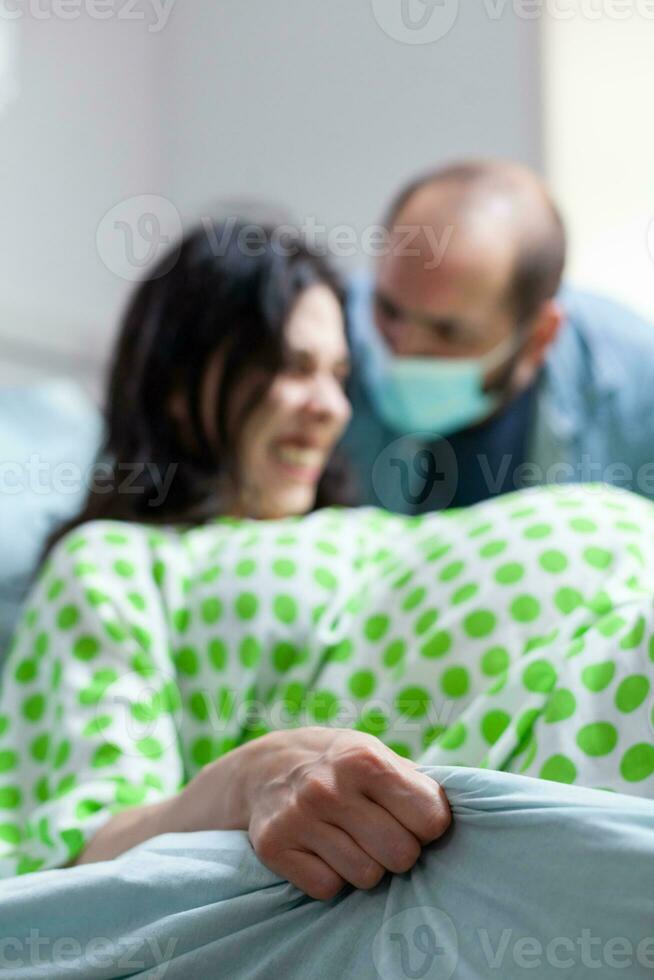 Pregnant woman trying to delivery baby in hospital ward, having husband beside her during caesarean surgery. Patient with pregnancy having paniful contractions during childbirth in maternity clinic photo