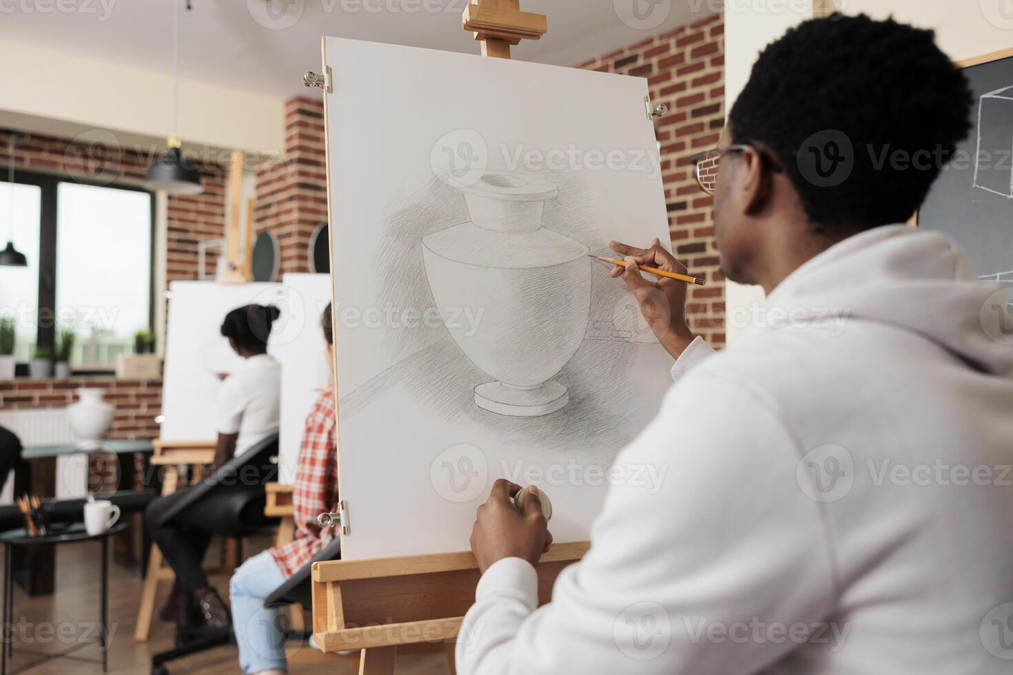 Young people friends attending drawing class, learning new skills together. Rear view of African American student guy sketching vase with pencil during group art lesson. Creativity and selfdiscovery photo