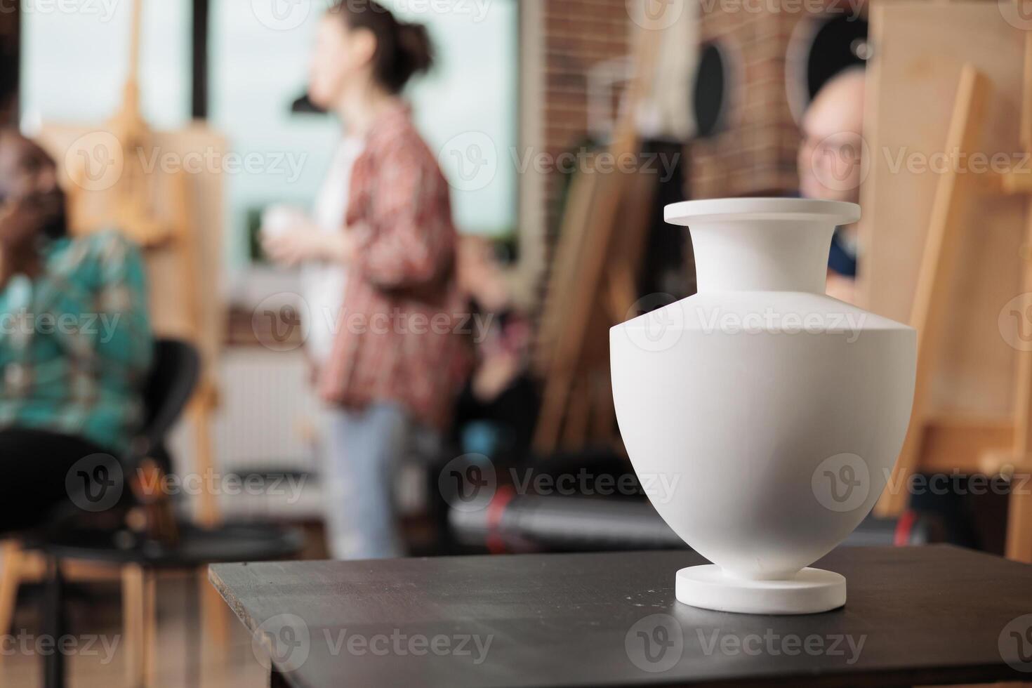 Still life drawing lessons. Ceramic vase standing on table in art room classroom, group of people learning to draw in class, attending creative workshop to learn new skills and boost creativity photo