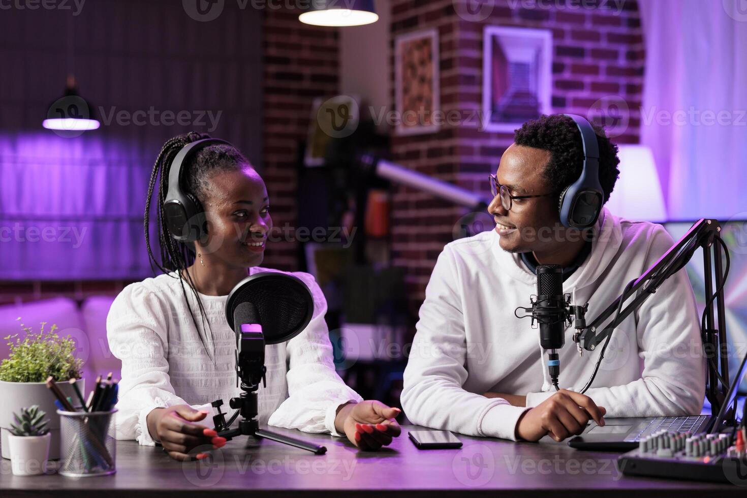 Team of smiling content creators hosting online show in living room studio, filming vlog, producing social media content. Vloggers recording internet production for streaming service photo