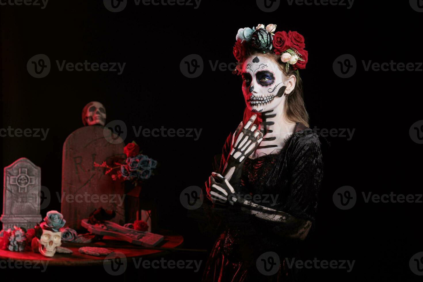 Beautiful woman wearing traditional skull body art and santa muerte costume in studio, acting like holy goddess of death to celebrate day of the dead. Mexican traditional holiday with make up. photo
