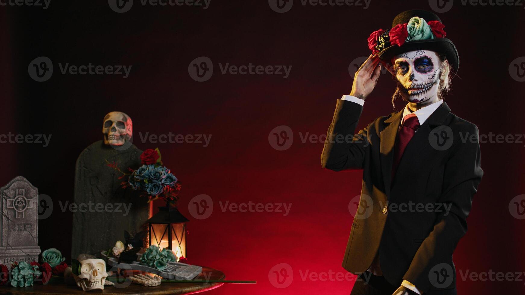 Santa muerte with suit and hat looking mysterious wearing festival skull body art, la cavalera catrina celebrating dios de los muertos in studio. Woman looking like holy mexican entity. photo