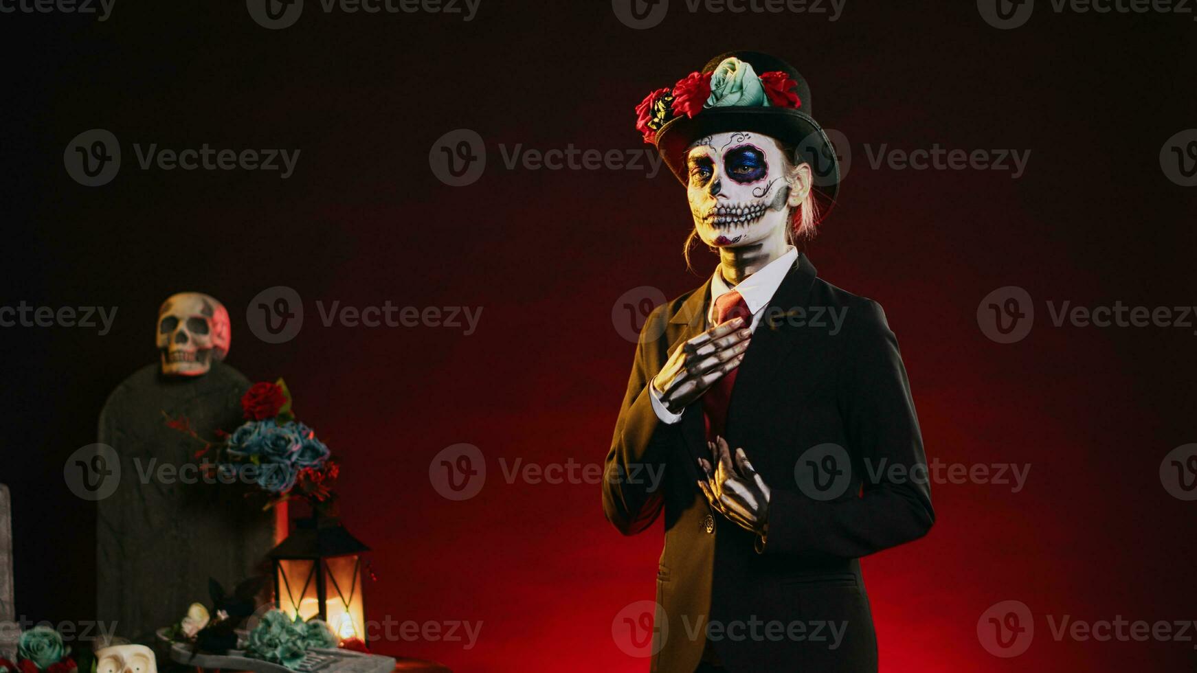 Lady santa muerte with suit and hat looking creepy wearing festival skull make up or body art paint, celebrating dios de los muertos holiday. Acting like la cavalera catrina. Handheld shot. photo