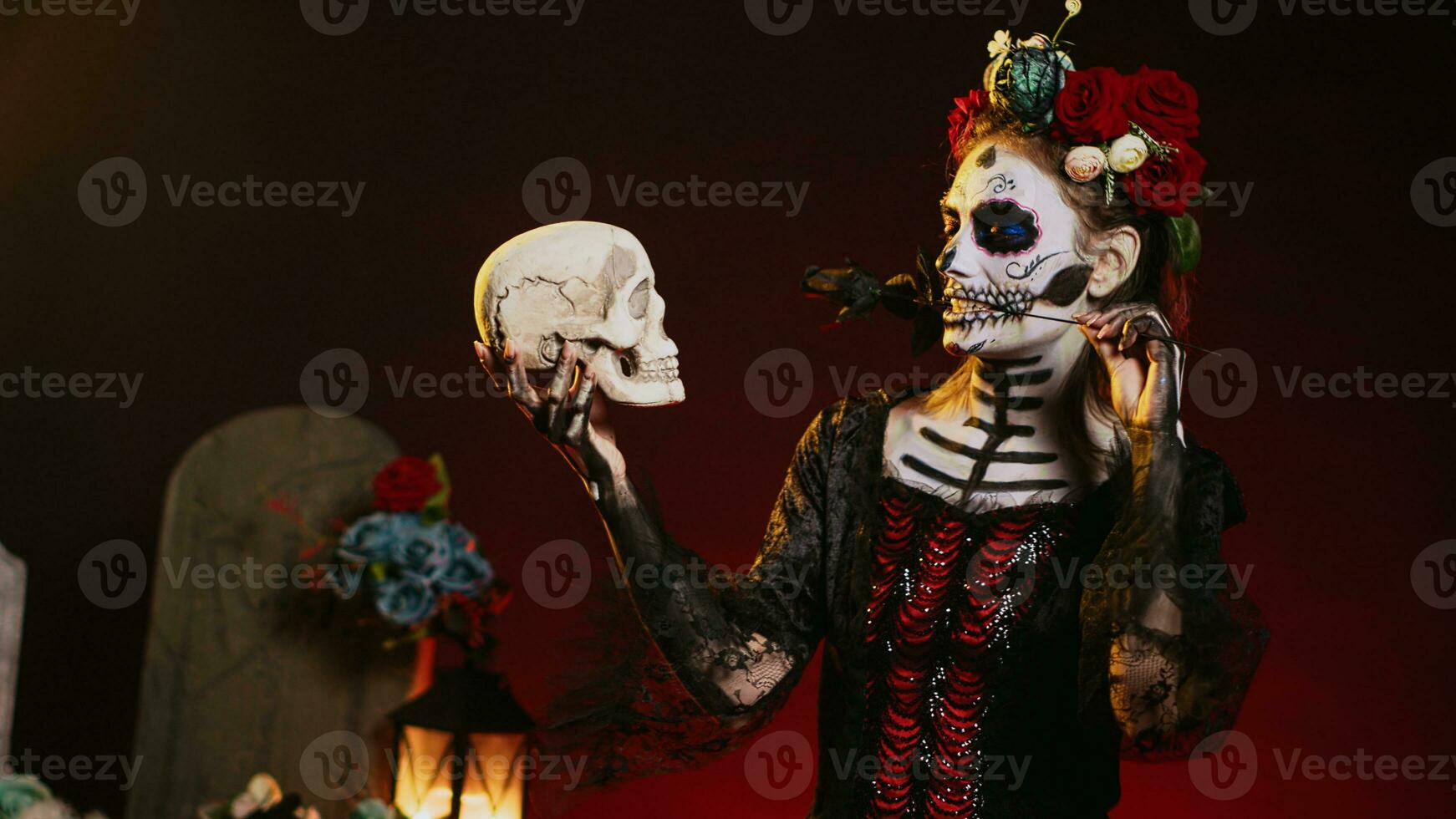 Horror female model acting flirty with skull and black roses, wearing traditional body art to celebrate mexican holiday. Looking like goddess of death on dios de los muertos ritual. Handheld shot. photo