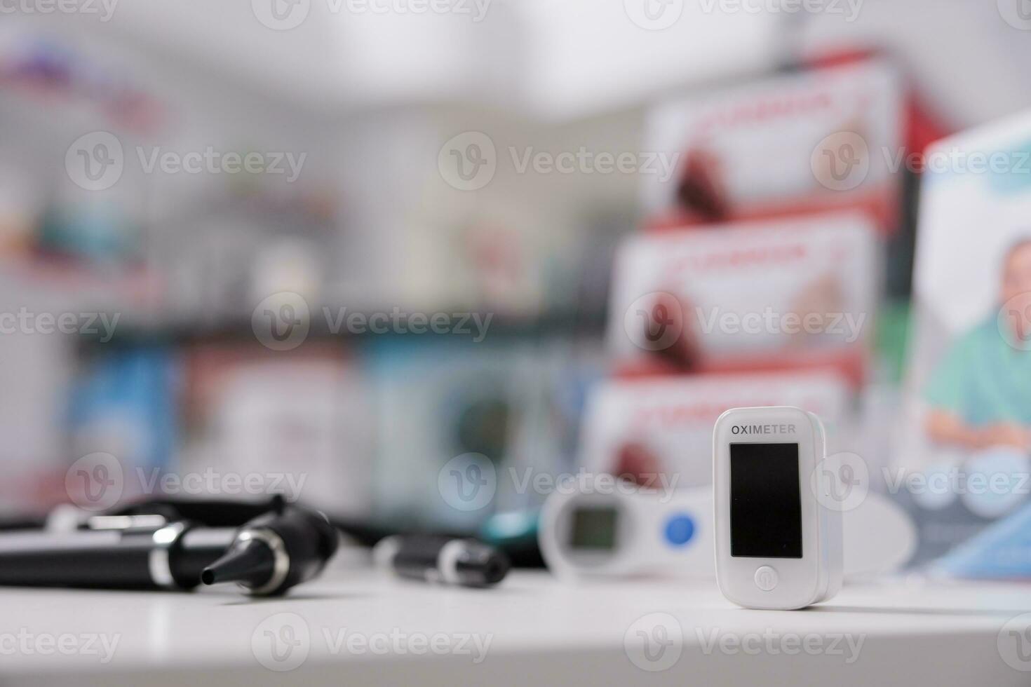Medical oximeter standing on table in empty drugstore ready to be used by client, digital device to measure oxygen saturation. Pharmacy filled with medicaments, vitamins and pharmaceutical products photo