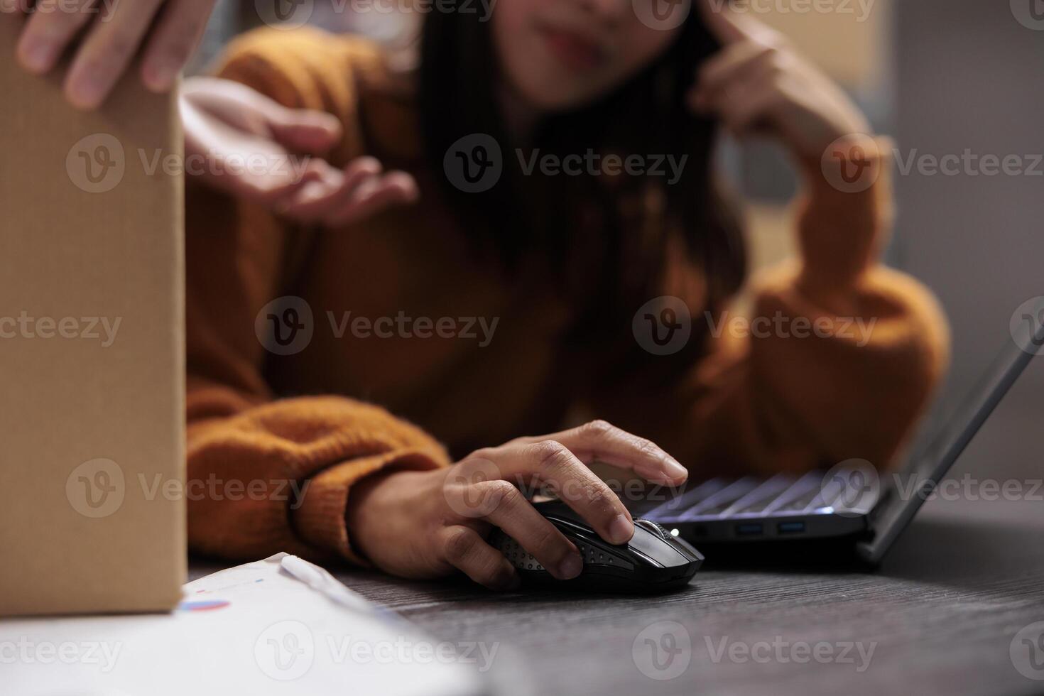 Warehouse employee managing product inventory on laptop while working at desk in postal storage room. Shipment manager checking orders list while using computer mouse close up photo