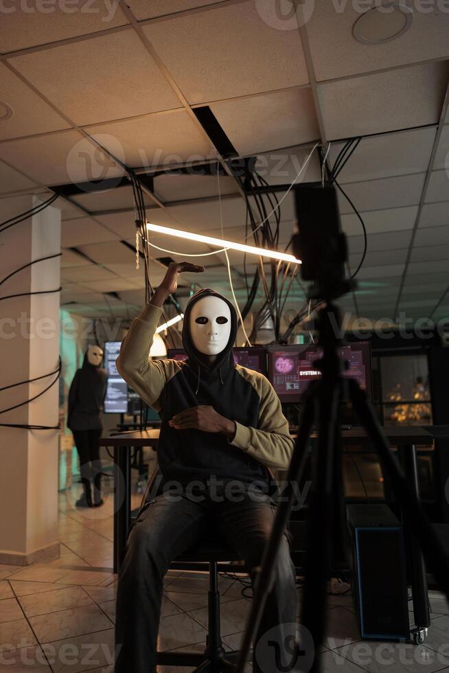 Mysterious criminal threatening to leak information on live broadcast, committing cyberattack and fraud. Anonymous scammer recording video on camera, asking victim money for ransom. photo