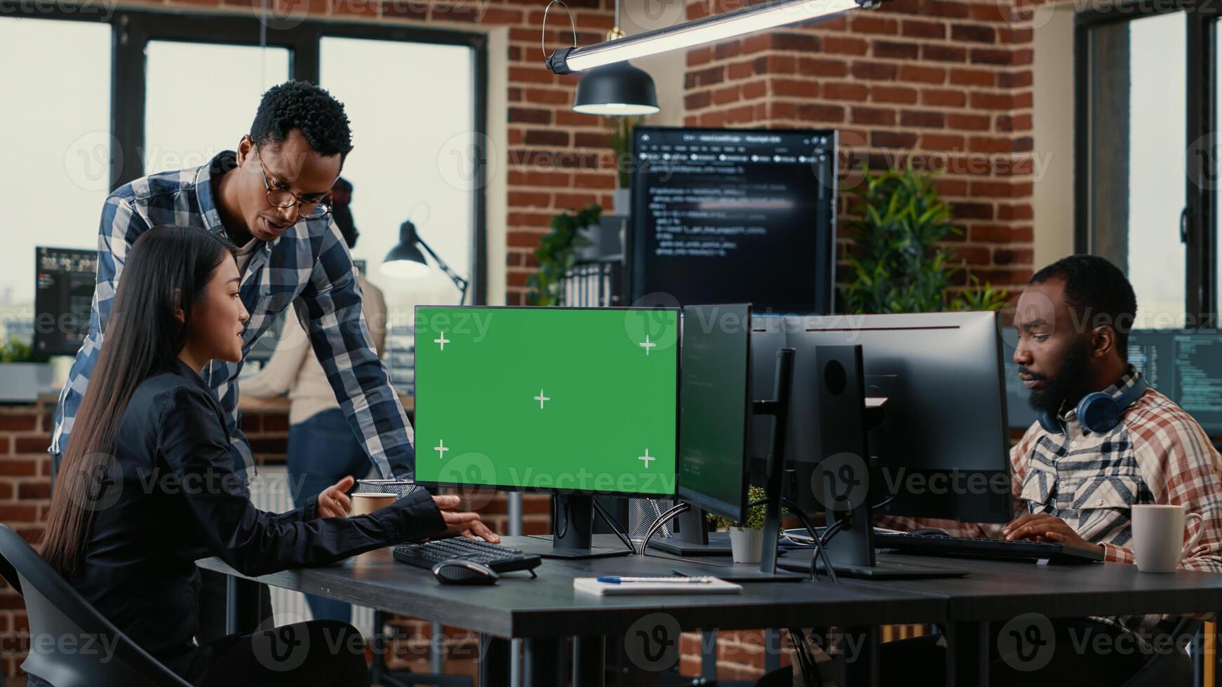 Two software developers analyzing source code looking at green screen chroma key mockup with coworker sitting at desk writing algorithm. Software developers working on artificial intelligence project. photo