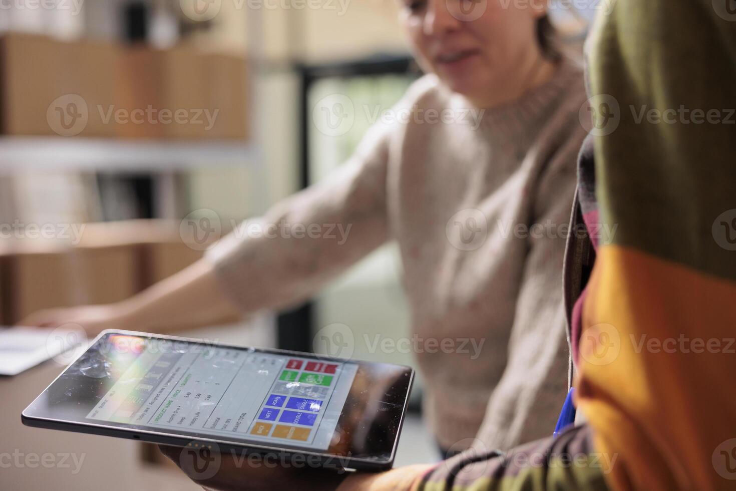 Stockroom team analyzing online orders on tablet computer, preparing packages for delivery in warehouse. Diverse employees working at goods inventory, typing report on digital device photo