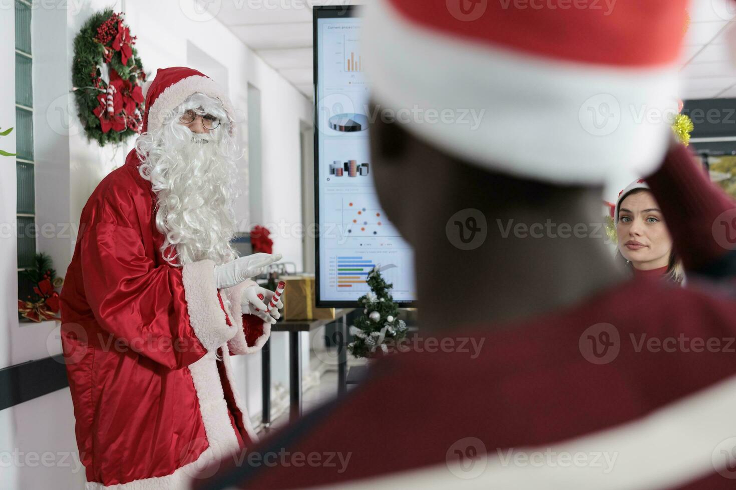 Public speaker dressed as Santa Claus inspiring employees to advance their careers in festive decorated office. Coworking meeting attendees learning important industry skills during holiday season photo