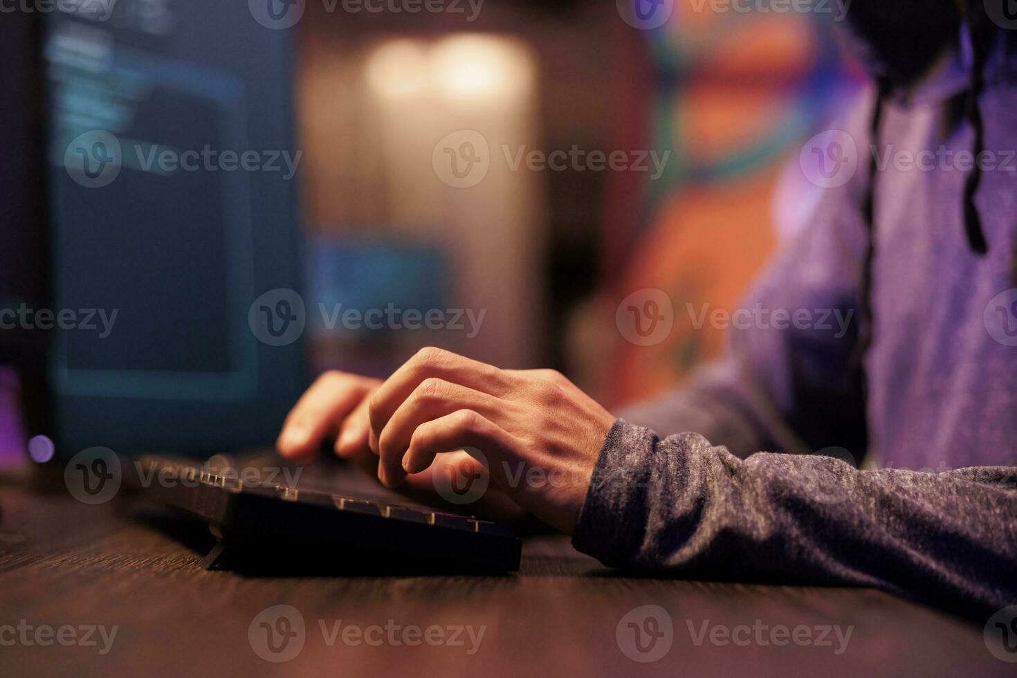 Hacker hands writing virus software code and typing on keyboard. Young internet criminal programming ransomware and cracking password to break into computer system with close up on arms photo