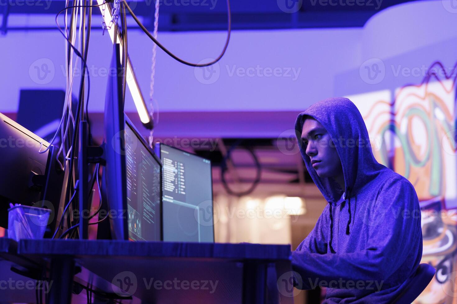 asiático hacker agrietamiento web contraseña en computadora y codificación malicioso software. delincuente hackear en línea servidor y haciendo ddos ataque ilegal actividad en abandonado almacén foto