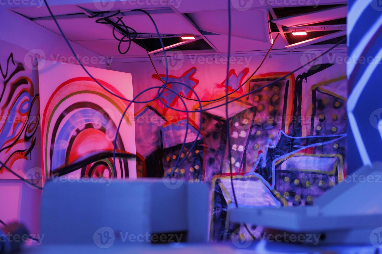 Demolished old building with purple and pink lights glowing in darkness of ruins and disintegration. Messy deserted warehouse with graffiti on rusty walls, fluorescent neon light. photo