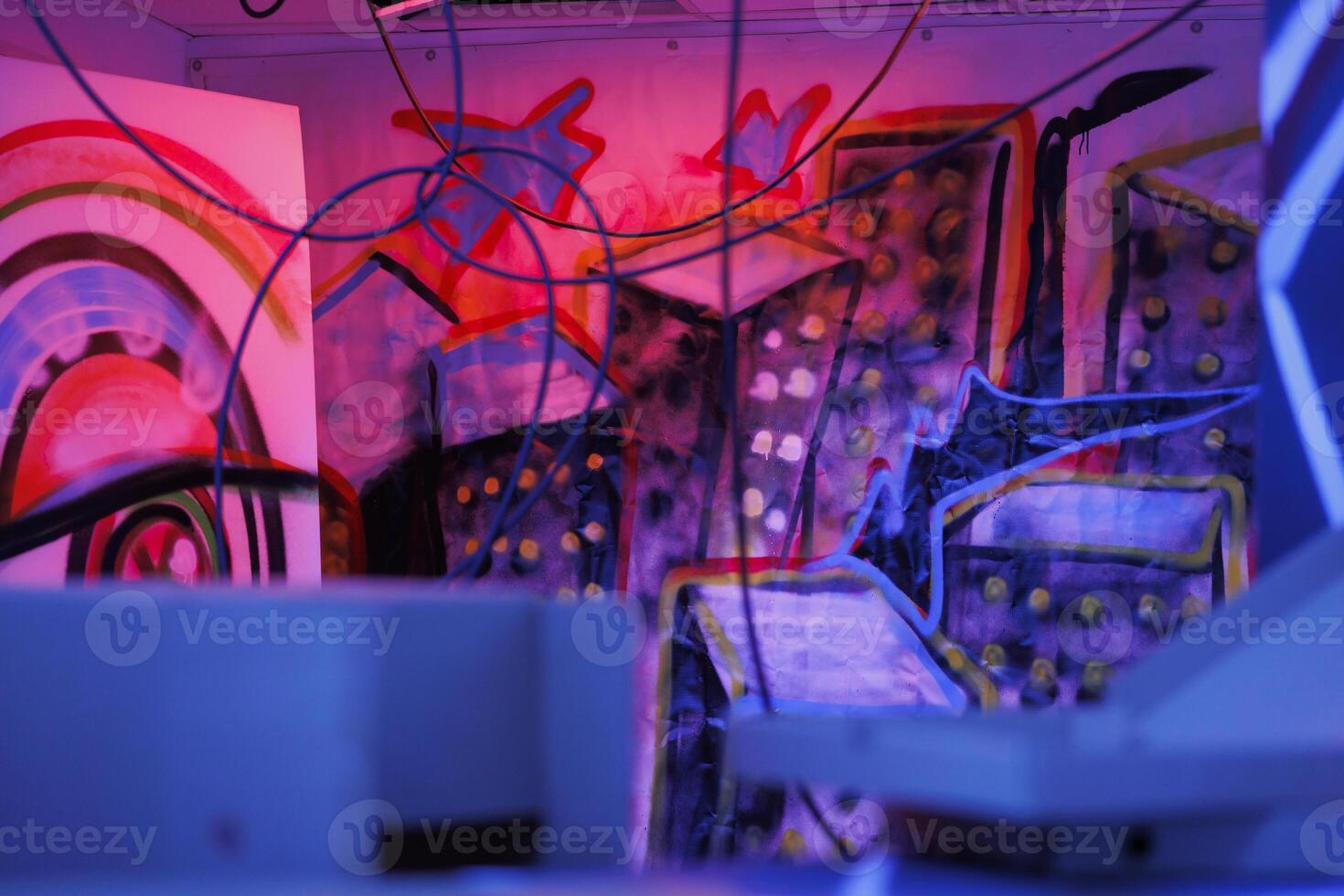 Rusty structure of warehouse with bright neon lights in state of ruins, looking creepy. Abandoned building showing signs of disintegration, glowing in dark with fluorescent purple light. photo