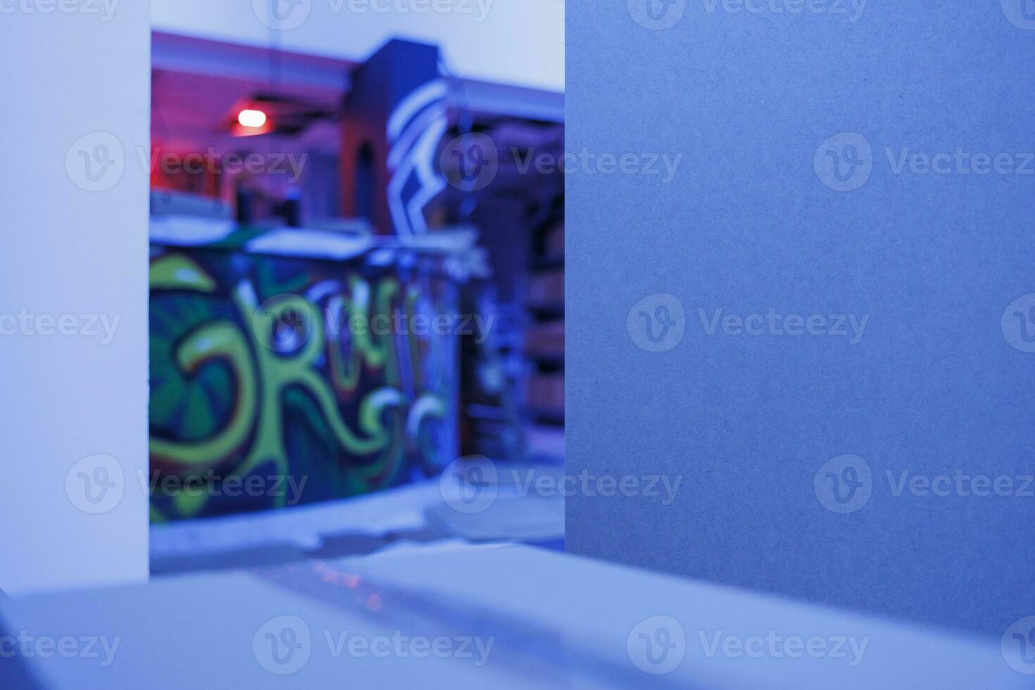 Old crumbling warehouse with purple bright lights, spray paint graffiti glowing under fluorescent lights in abandoned place. Deserted messy space with neon blue glow, rusty warehouse. photo