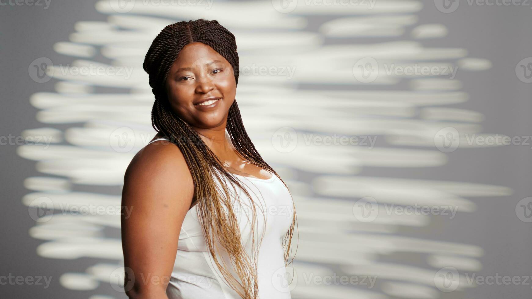 perfecto confidente niña posando en cámara y publicidad cuidado del cuerpo Campaña con belleza productos cosméticos. edificante mujer con luminoso Mira interino amable, promoviendo feminidad en estudio. foto