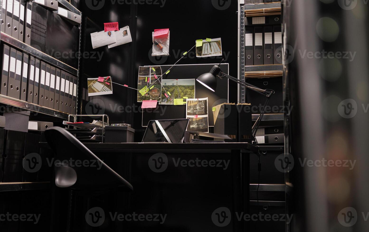 Empty dark police detective room with murder case investigation process on board. Suspect photographs connected with clues hanging on wall and file folders on racks in investigator agency office photo