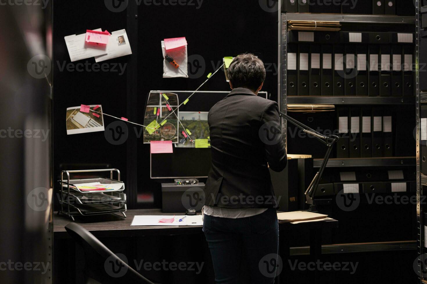 federal agente mirando a investigación tablero comprobación misterioso crimen evidencia, trabajando tarde a noche en fi oscuro habitación. policía oficial descubrimiento confidencial información acerca de desaparecido persona foto