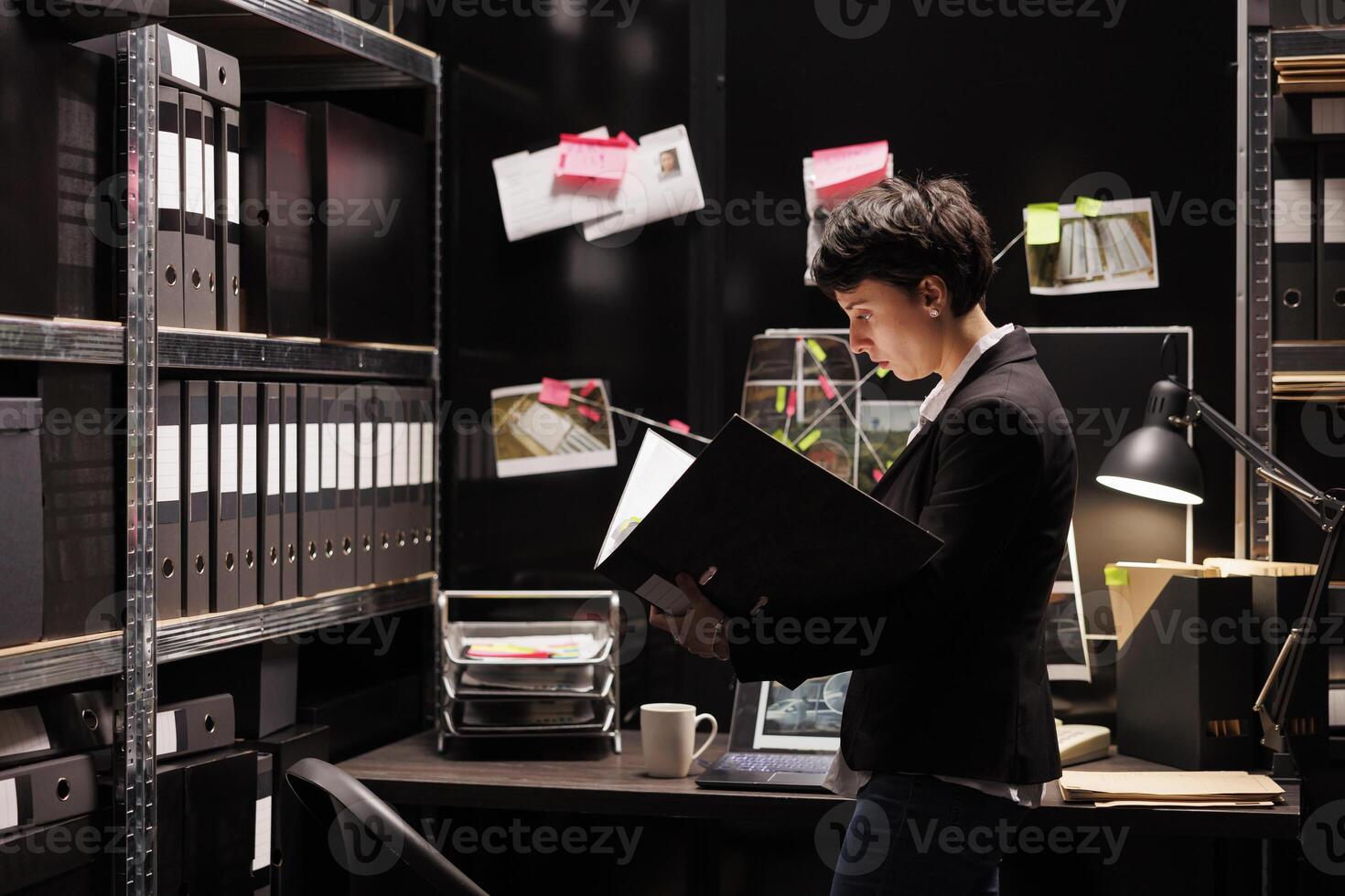 Private detective reading police private report, discovery confidential information about mysterious crime. Federal agent working late at night in arhive room. Investigation cooncept photo
