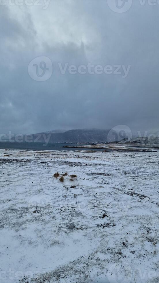 Wintry landscape with frosty fields in icelandic region, massive snowy mountains hilltops and frozen lands. Winter wonderland roadside landscape with highlands and hills. photo