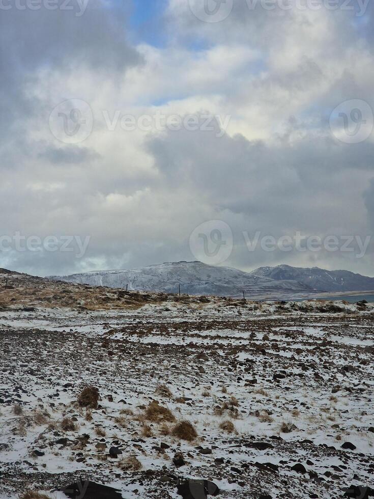 Nevado montañas y invernal pastos en Islandia naturaleza, hermosa nórdico paisaje cubierto en nieve. fantástico masivo rocoso cimas de las montañas y marrón escarchado campos junto a campo. foto