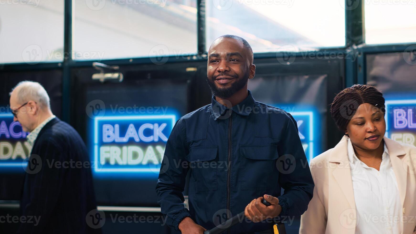 Security guard in clothing store wearing uniform and presenting on duty at black friday promotional event. Shopping center protective agent with security baton ensuring safety. photo