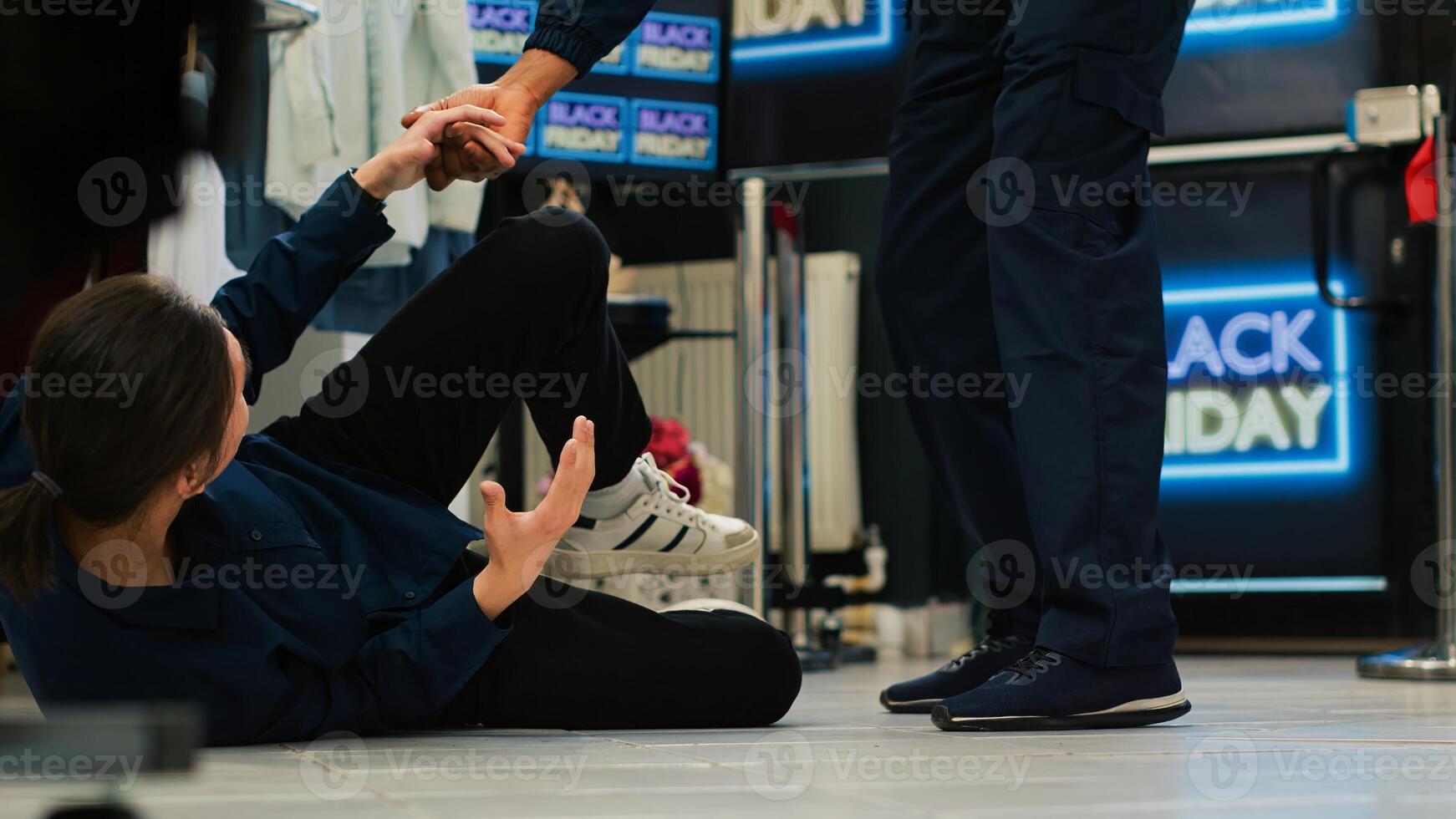 Black friday shopping madness concept. Aggressive shoppers pushing young man on the floor, rushing to enter clothing store. Asian customer getting hurt during seasonal sales event. photo