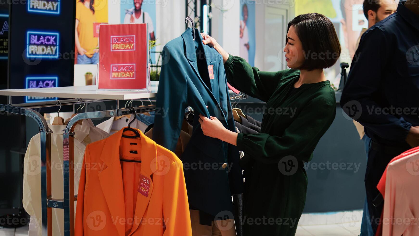 Female client looking at shirt with red price tag during black friday seasonal sales, shopping on fashion outlet. Shoppers buying clothes at discounted prices in clothing store. photo
