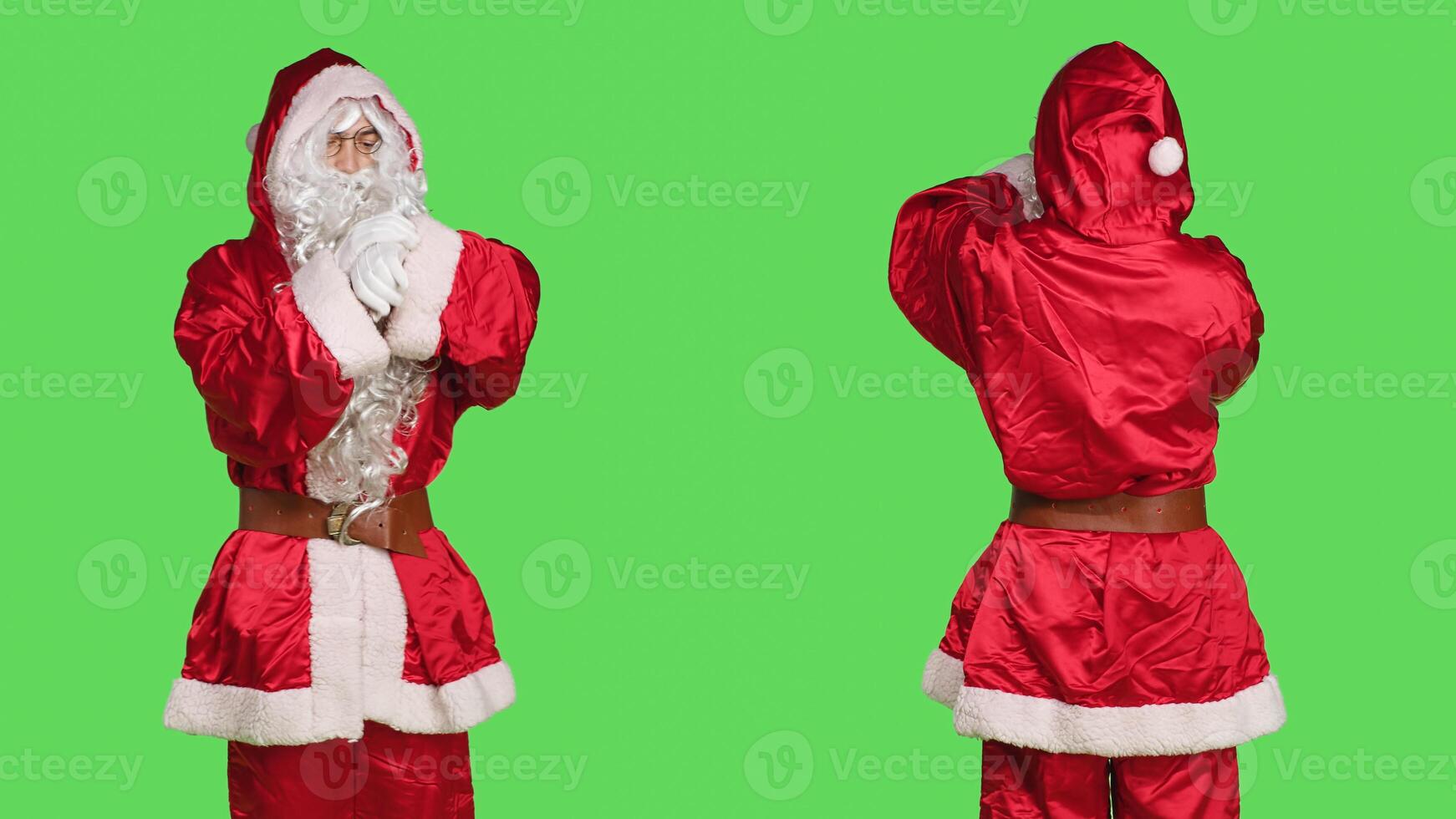 Impatient santa claus in suit checking time on wristwatch while he stands over greenscreen backdrop. Young adult dressed in festive winter character costume waiting for something, xmas spirit. photo