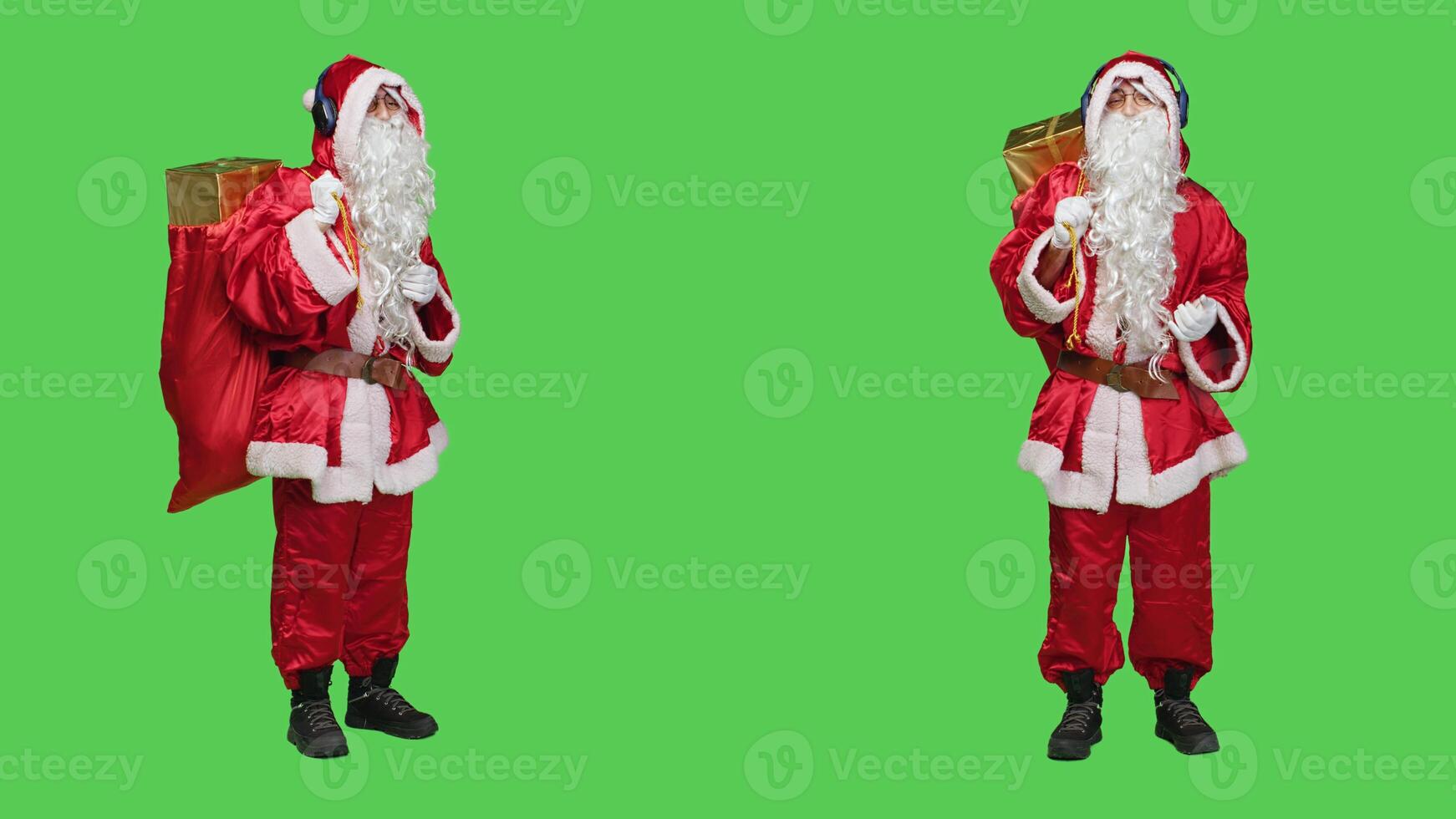 Young man dancing on songs in studio, acting like father christmas and listening to music on headphones. Modern saint nick character enjoying dance moves with audio headset, red costume. photo