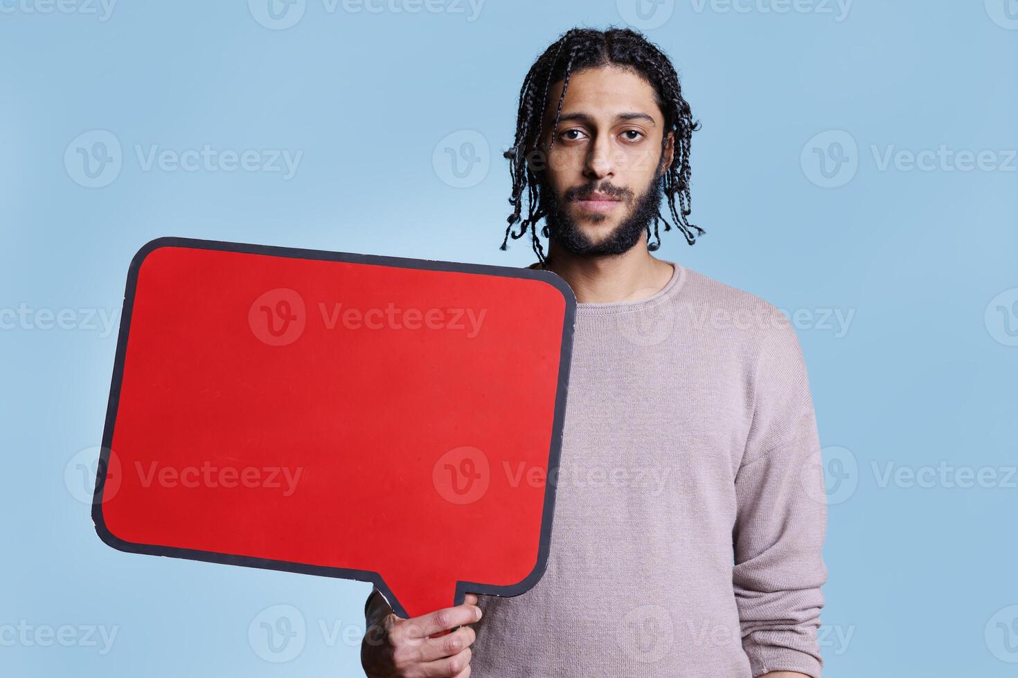 Arab man holding red empty banner with place for text for advertising mock up and looking at camera. Model standing with blank dialog frame for message with copy space portrait photo