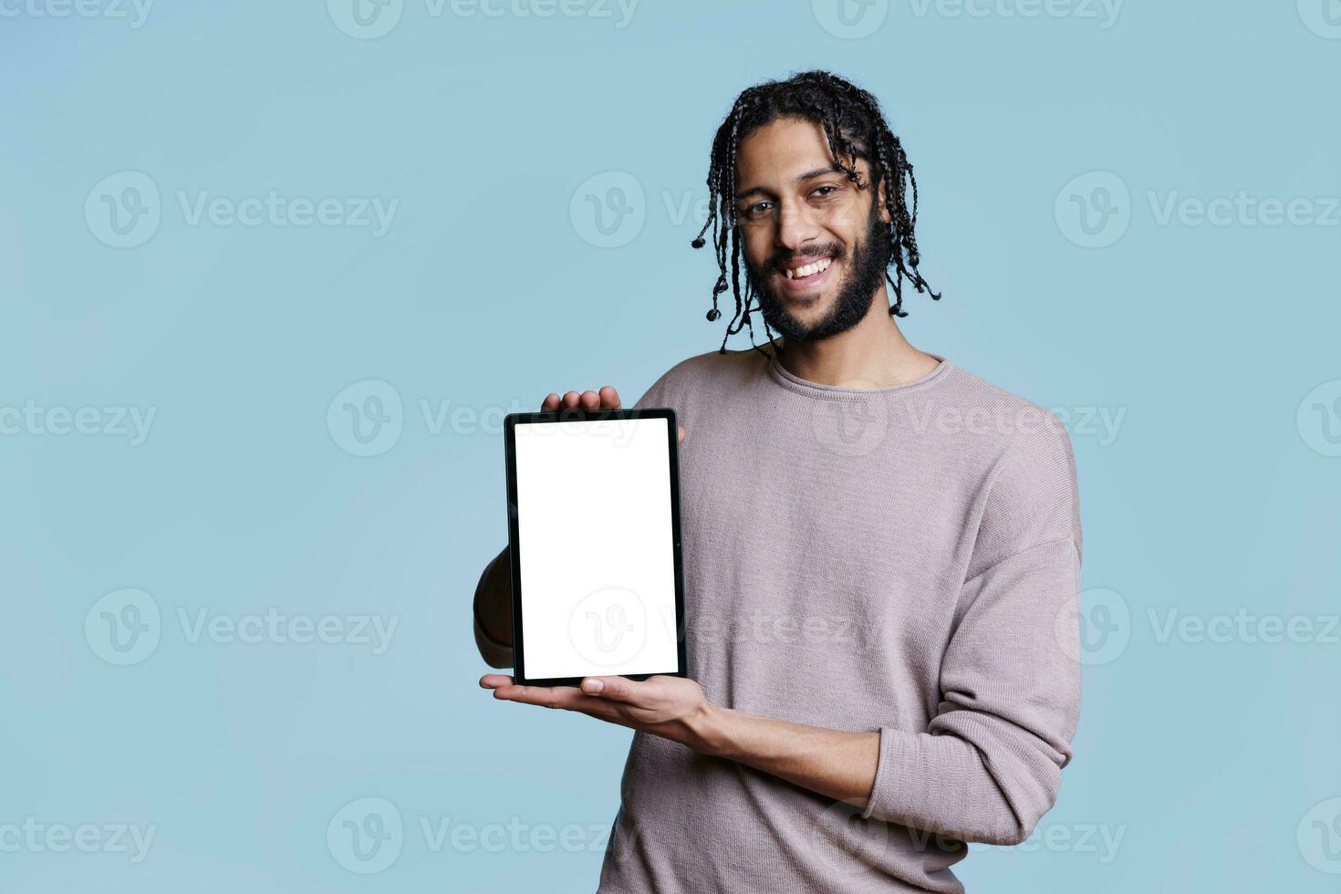 Cheerful arab man holding digital tablet with blank touchscreen and looking at camera. Smiling person showing portable device with empty white screen background for software ads photo