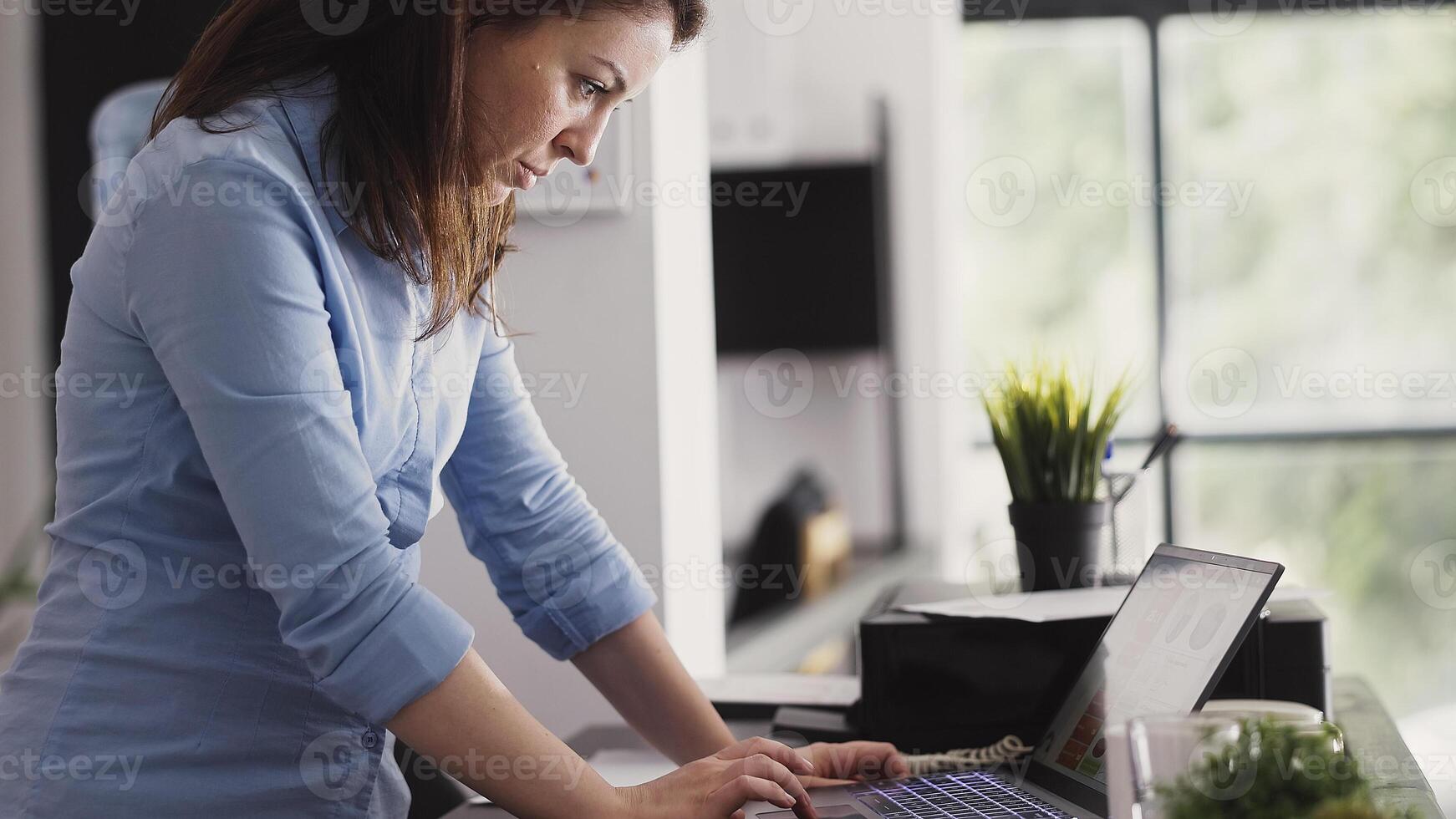 Female entrepreneur working on laptop to plan report, using online data analytics on computer. Young employee analyzing corporate statistics for management, professional project. Handheld shot. photo