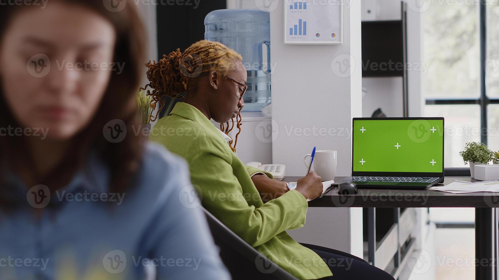 Executive assistant analyzing green screen display on pc, using laptop with chroma key copyspace display. Office employee looking at isolated mockup screen in business coworking space. photo