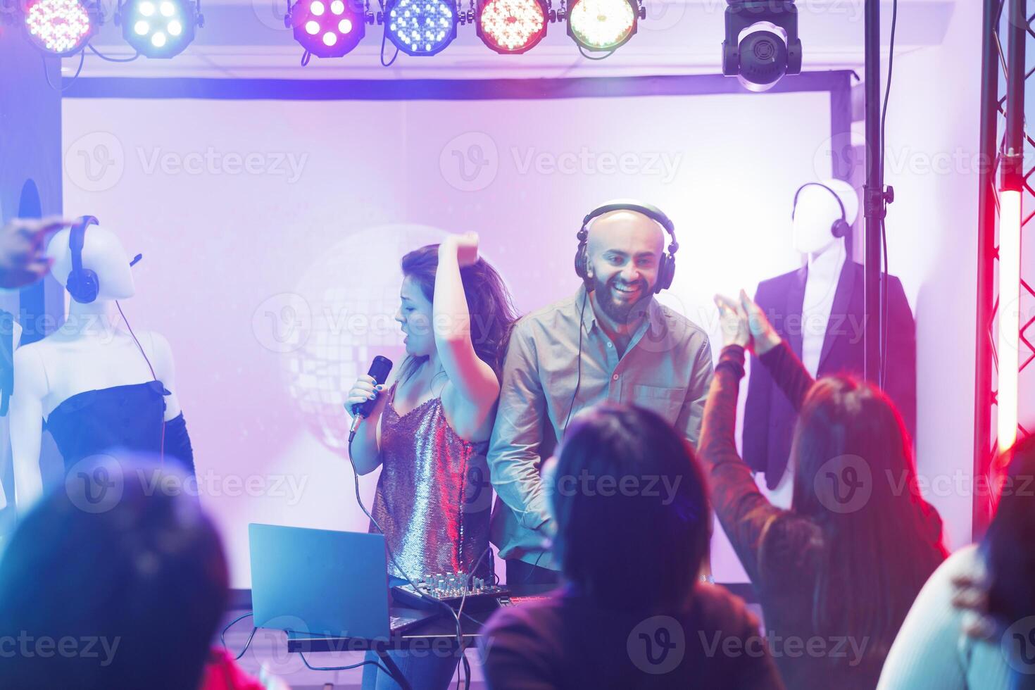 DJ y cantante ejecutando en etapa mientras personas bailando y disfrutando espectáculo en Club nocturno. diverso multitud clubbing y ir de fiesta en pista de baile a electrónico música banda concierto en club foto