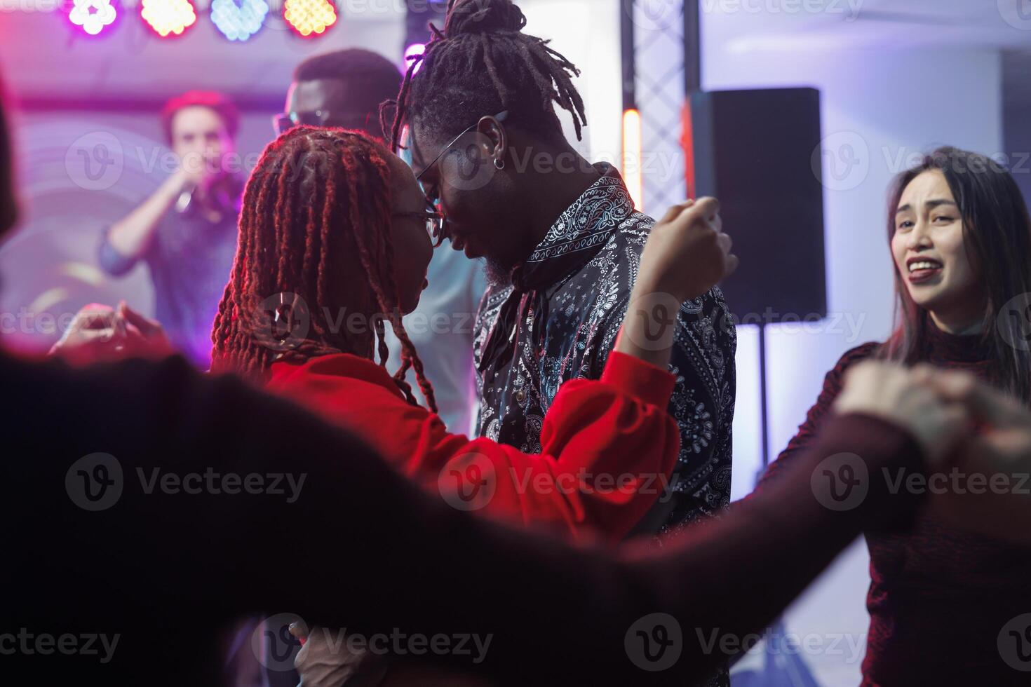 Young couple in love dancing together and hugging in crowded nightclub. African american man and woman embracing while moving and showing affection on dancefloor surrounded with clubbers photo