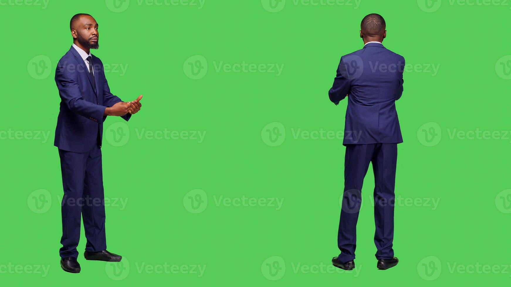 Young adult in suit having symphony concert at opera, conducting choir music posing over green screen backdrop. Optimistic conductor working as choirmaster having musical event in studio. photo