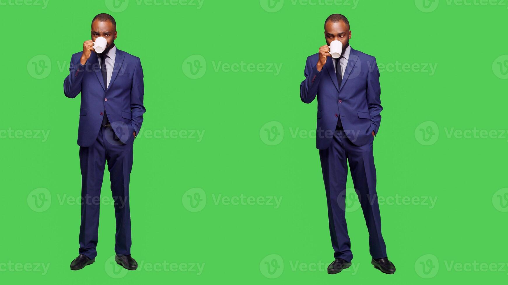 Male manager drinking cup of coffee on camera, serving caffeine beverage over full body green screen. Corporate worker enjoying hot refreshment drink, wearing business suit in studio. photo