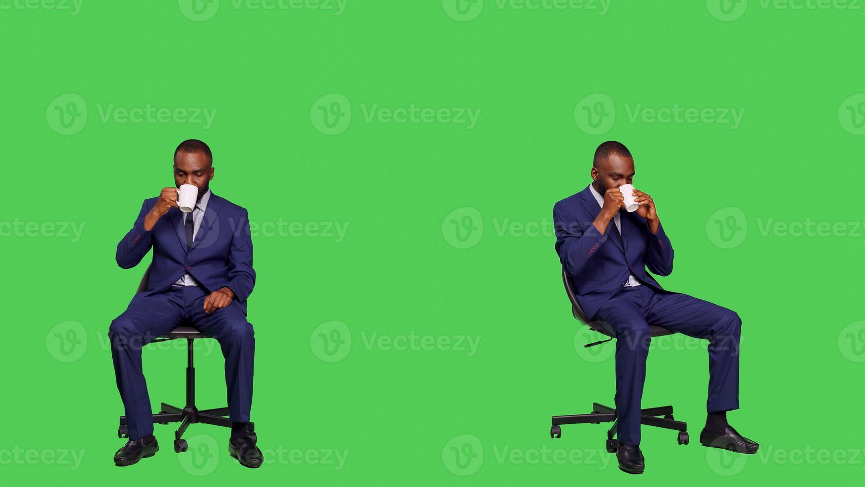 Business manager serving cup of caffeine beverage, sitting on chair and having coffee drink in studio. Young adult employee wearing office suit over full body green screen backdrop. photo