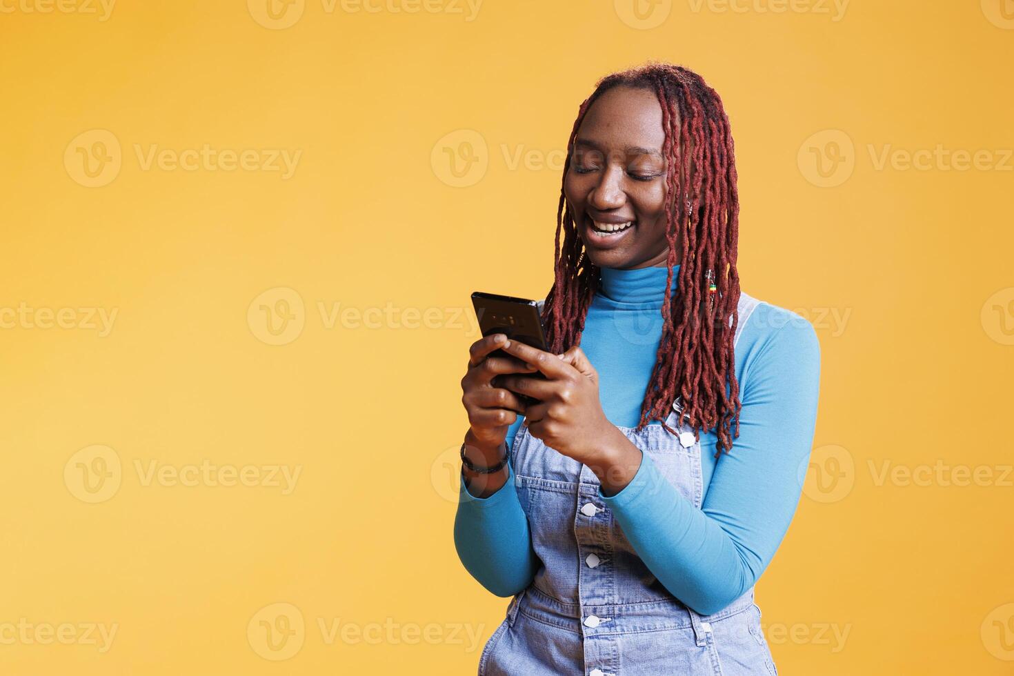 African american girl using mobile phone on holiday journey, browsing social media app in studio. Young person checking online internet page on smartphone, weekend activities. photo