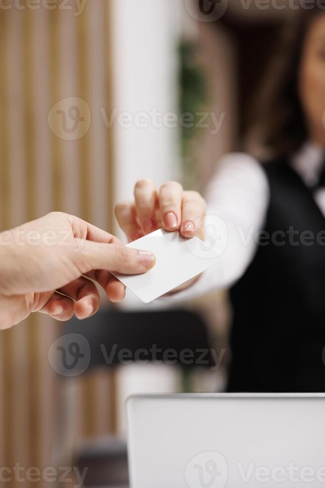 Businessman taking room key card in lobby, gaining access to accommodation before attending conferences on business trip. Young adult doing check in at hotel front desk. Close up. photo